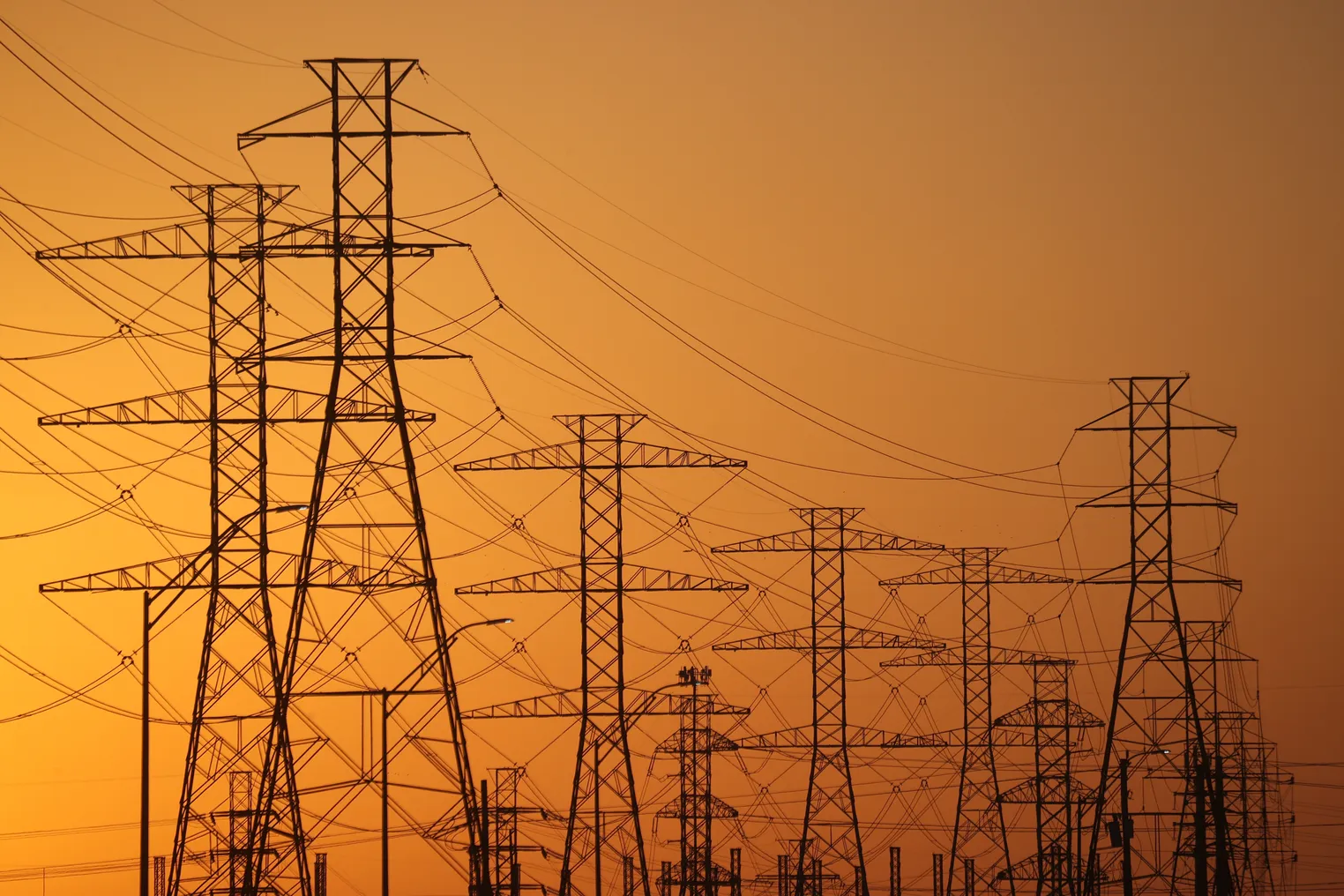 High voltage transmission lines are seen against an orange sky in Texas.