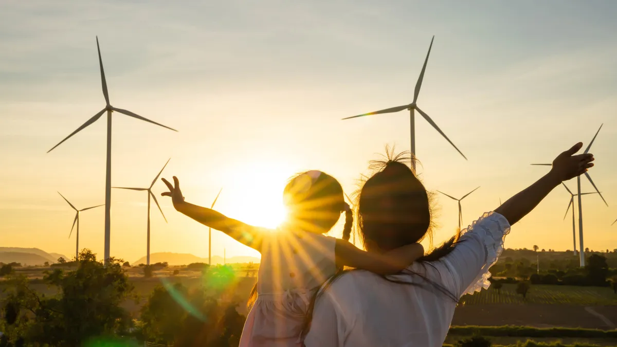 An adult and a child looking at a field with wind turbines