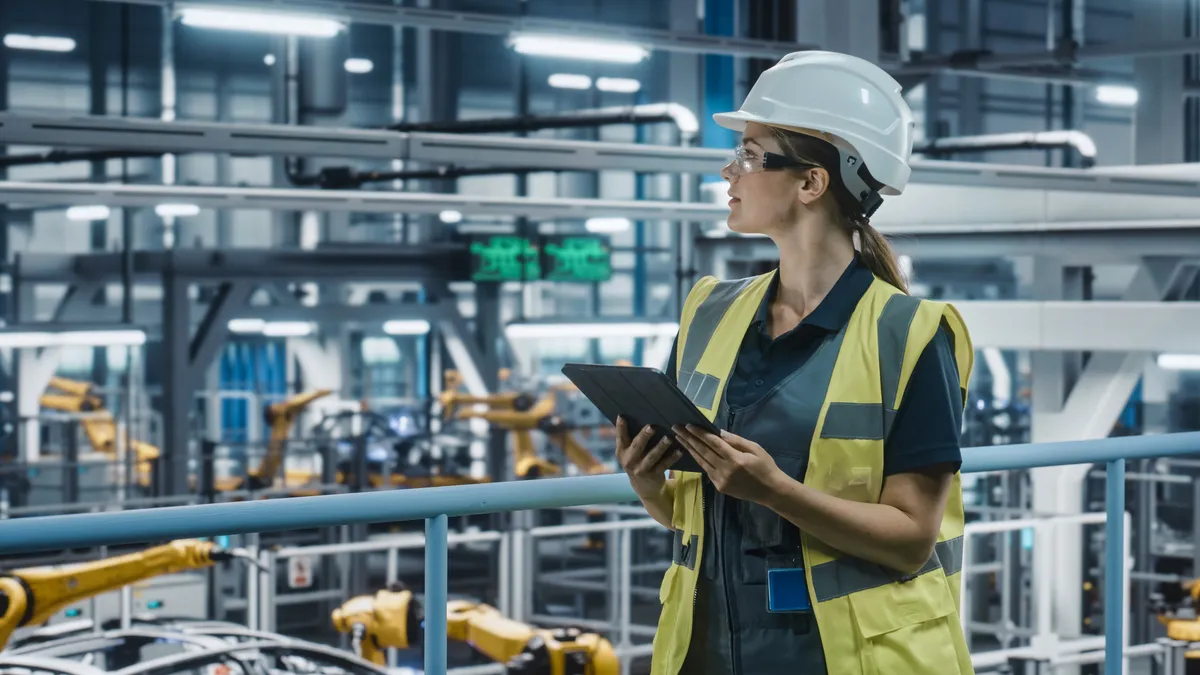 Female Car Factory Engineer in High Visibility Vest Using Tablet Computer