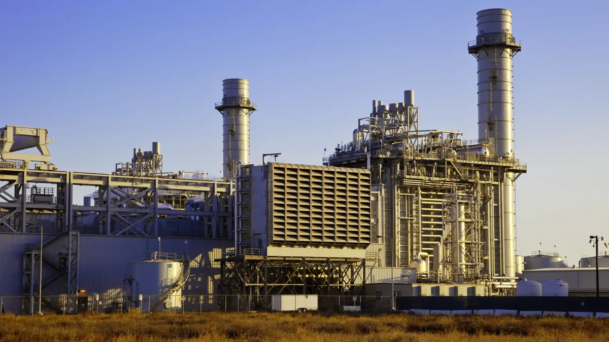 A natural gas-fired turbine power plant with it's cooling towers rising into a blue sky.