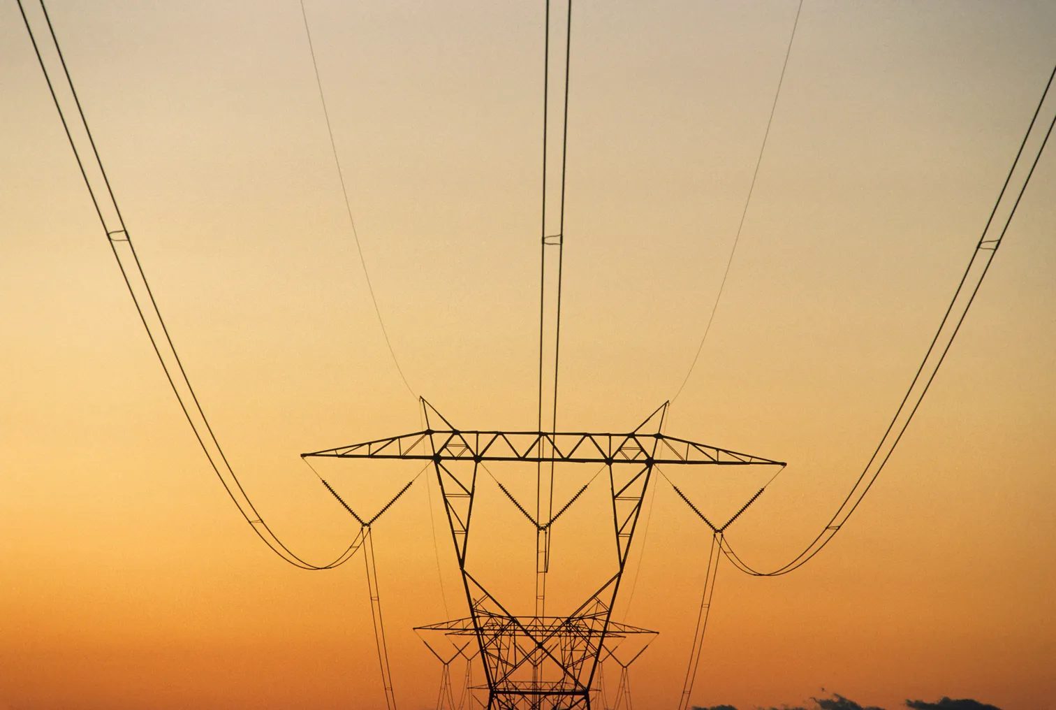 Pylon with power lines against reddish sky at sunset, rural North Carolina, USA.