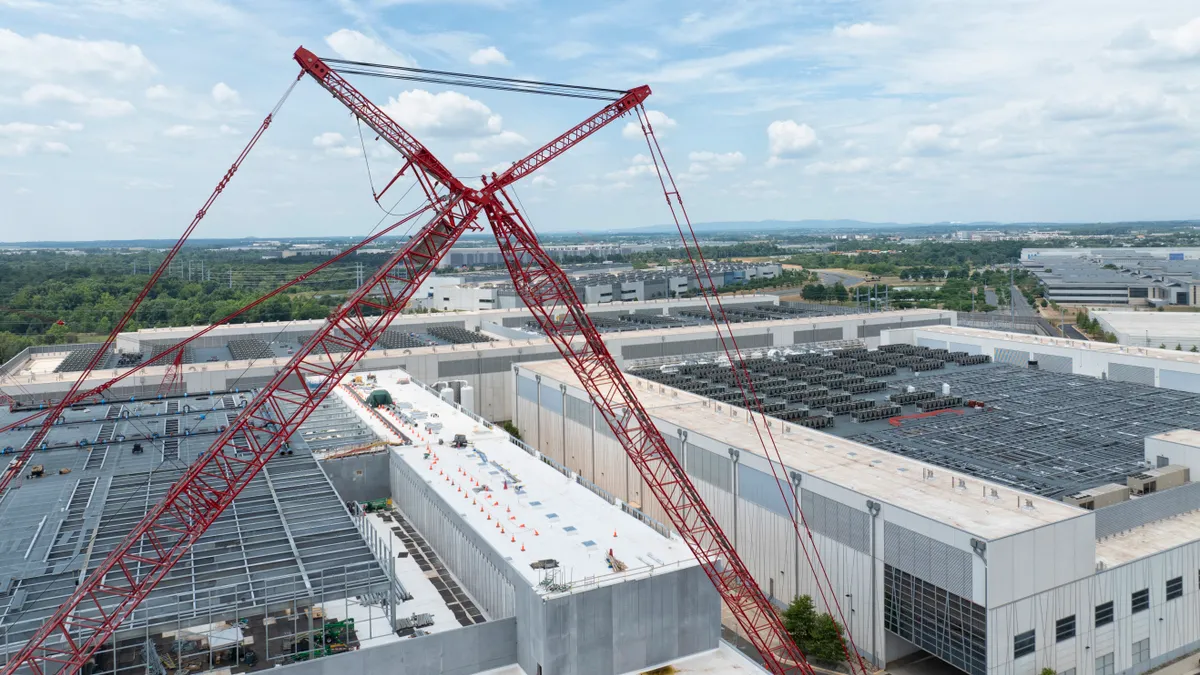 A red crane in front of large concrete buildings.