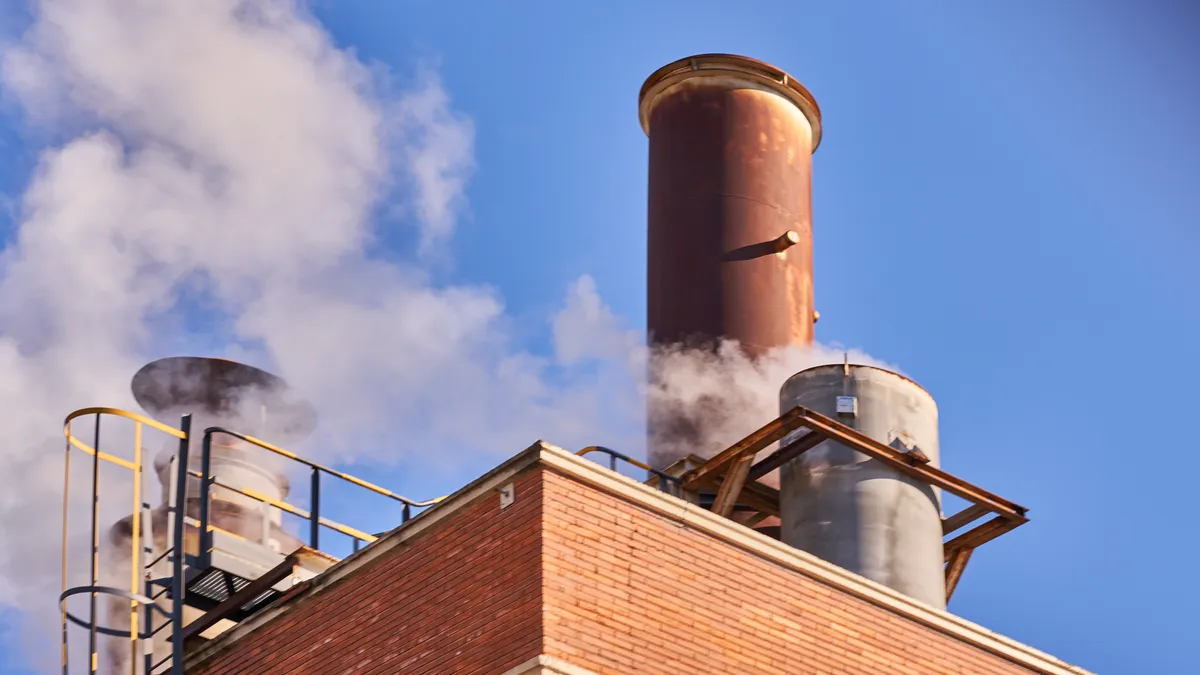 A view of an industrial chimney releasing fumes, steam and polluting gases