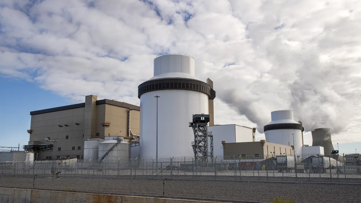 Two tall white industrial structures stand among an array of buildings.